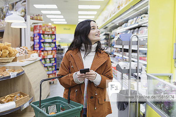 Frau mit Smartphone beim Einkaufen im Supermarkt