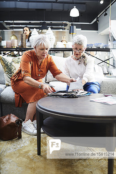 Ältere Frauen betrachten Stoffmuster in einem Möbelhaus