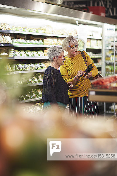 Ältere Frauen mit Smartphone beim Lebensmitteleinkauf im Supermarkt