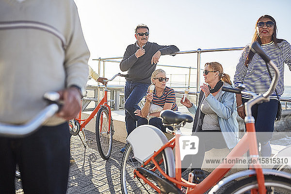 Active senior friend tourists with bicycles eating ice cream