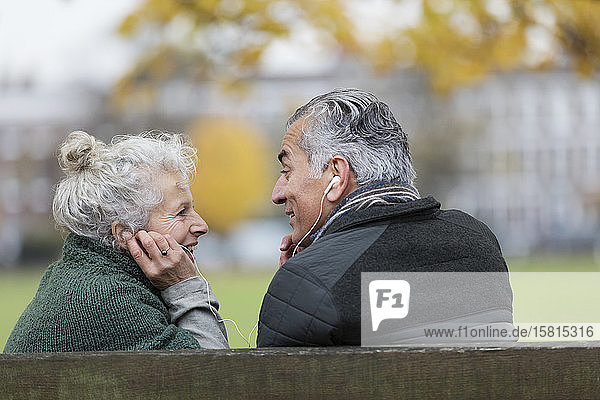 Glückliches älteres Paar mit Kopfhörern  das im Park Musik hört