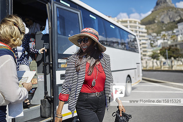 Lächelnde aktive ältere Touristin beim Aussteigen aus dem Reisebus