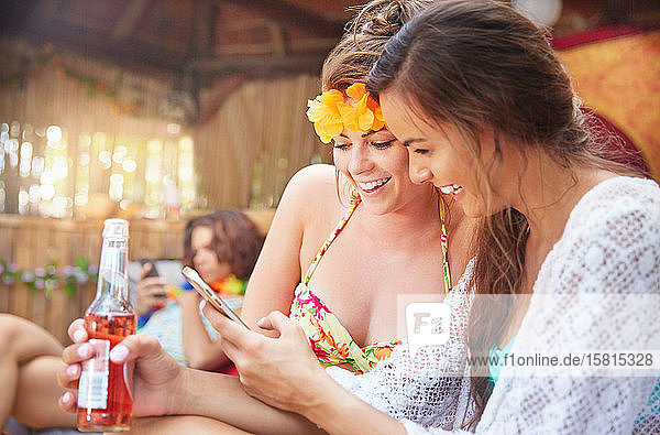Junge Frauen Freunde trinken und Texting mit Smartphone im Sommer Poolside