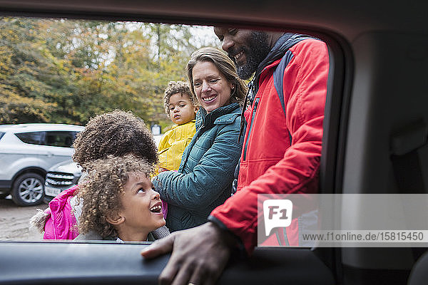 Glückliche multiethnische Familie vor dem Auto