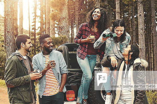 Junge Freunde hängen ab  trinken Kaffee am Jeep im Wald