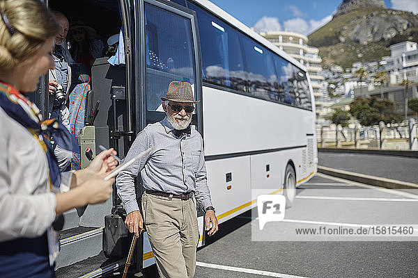 Aktiver älterer männlicher Tourist beim Aussteigen aus dem Reisebus