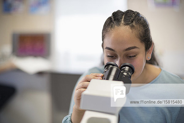 Studentin mit Mikroskop im Klassenzimmer