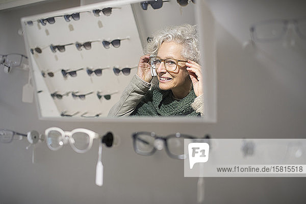 Ältere Frau probiert in einem Optikergeschäft eine Brille an