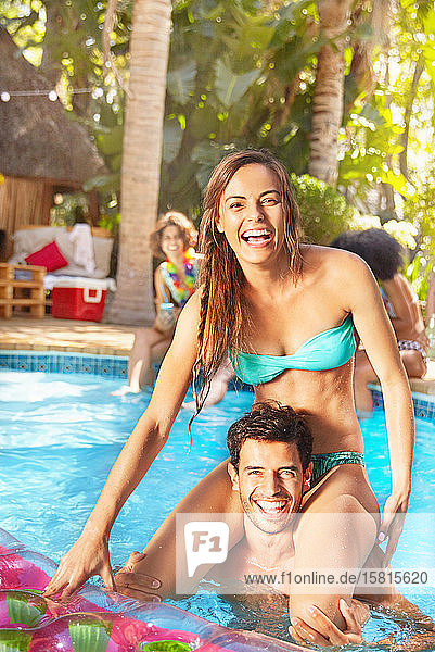 Portrait lächelnd  zuversichtlich  junges Paar spielt Huhn in sonnigen Sommer Schwimmbad