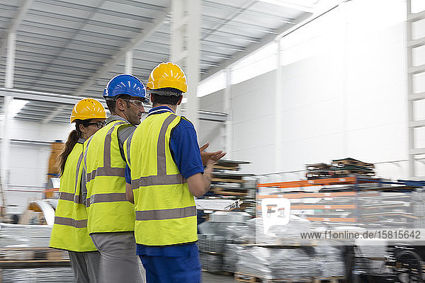 Supervisor and workers walking and talking in warehouse