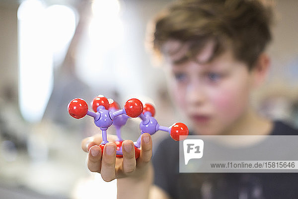 Junge Student hält und untersucht Molekularstruktur