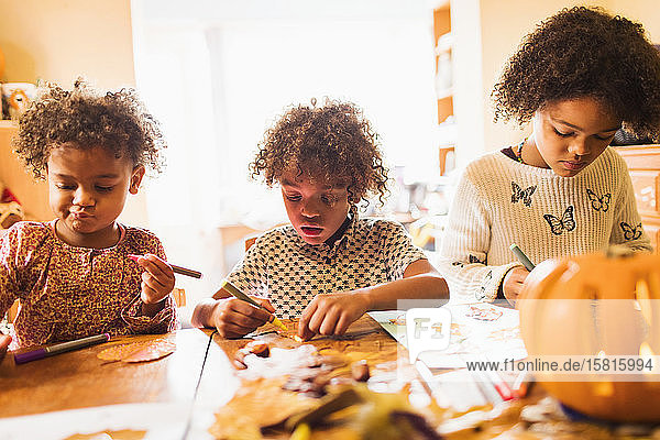 Brother and sisters making autumn crafts at table