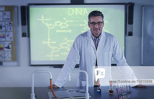 Porträt eines männlichen Lehrers der Naturwissenschaften  der an einer Projektionsfläche DNA-Unterricht erteilt
