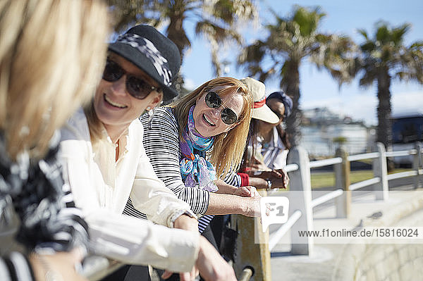 Lächelnde aktive ältere Frauen  die sich auf der sonnigen Strandpromenade unterhalten
