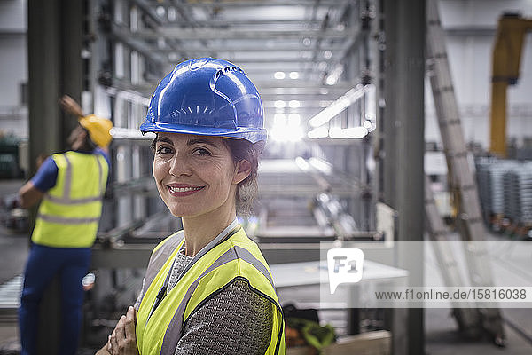 Porträt einer lächelnden  selbstbewussten Arbeiterin in einer Fabrik