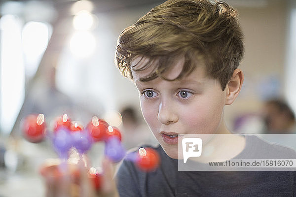 Neugieriger Junge  der ein Molekülmodell im Klassenzimmer untersucht
