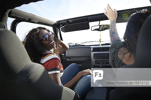Verspielte junge Frauen genießen die Fahrt im Jeep