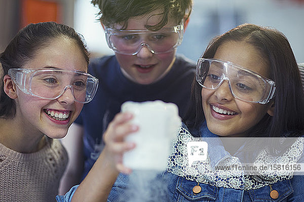 Neugierige  lächelnde Schüler  die eine chemische Reaktion beobachten und ein wissenschaftliches Experiment in einem Laboratorium durchführen