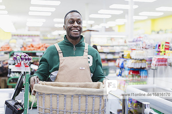 Porträt eines lächelnden  selbstbewussten männlichen Lebensmittelhändlers  der im Supermarkt arbeitet