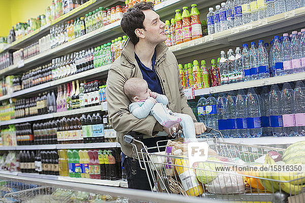 Vater mit Baby beim Einkaufen im Supermarkt