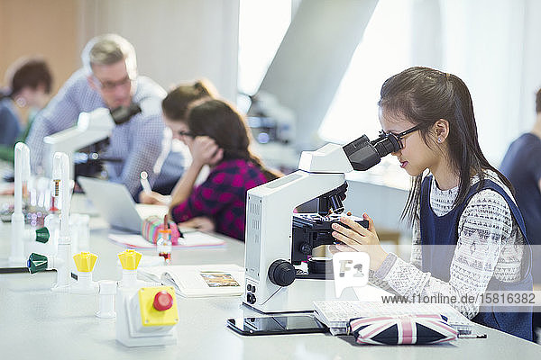 Girl student using microscope  conducting scientific experiment in laboratory classroom