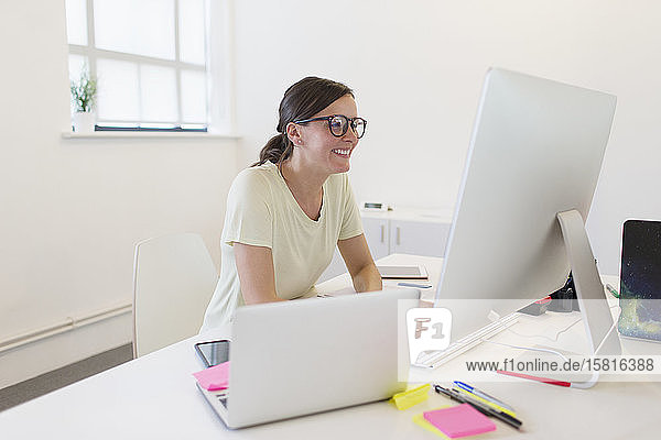 Lächelnde Geschäftsfrau bei der Arbeit am Computer im Büro