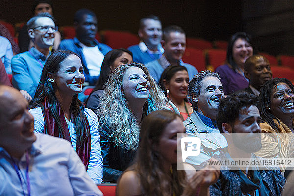 Smiling  enthusiastic audience in dark auditorium