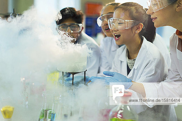 Erstaunte  neugierige Schüler  die eine chemische Reaktion beobachten und ein wissenschaftliches Experiment in einem Laboratorium durchführen