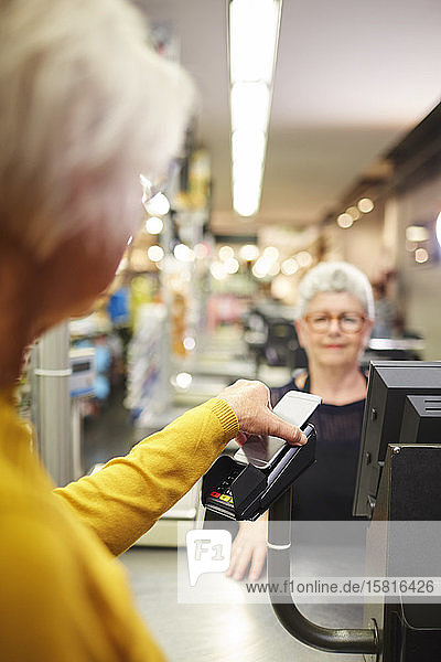 Kunde zahlt mit Smartphone an der Supermarktkasse