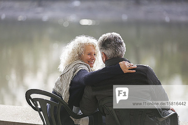 Zärtliches aktives Seniorenpaar  das sich am Parkteich umarmt