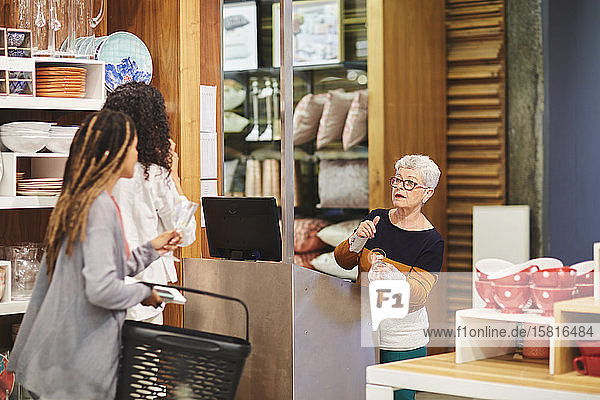 Senior cashier helping women shopping in home goods store
