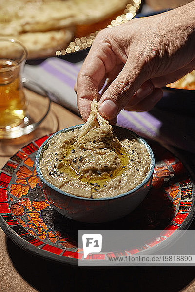 Ein Stück Brot in Baba Ghanoush-Dip tauchen