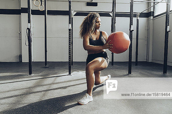 Junge Frau trainiert mit Medizinball im Fitnessstudio