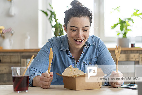 Portrait of woman sitting at table eating with wooden cutlery