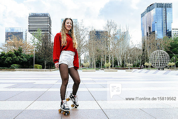 Portrait of happy young woman roller skating in the city