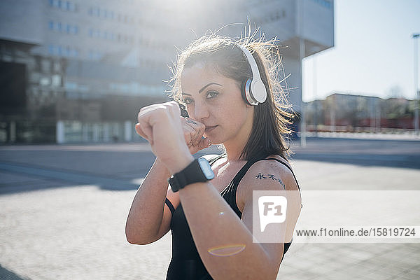 Porträt einer selbstbewussten  sportlichen jungen Frau mit Kopfhörer in der Stadt