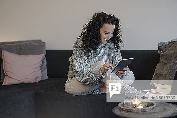Frau sitzt zu Hause auf der Couch  benutzt digitales Tablet  liest