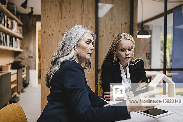 Mature and young businesswoman examining architectural model in loft office