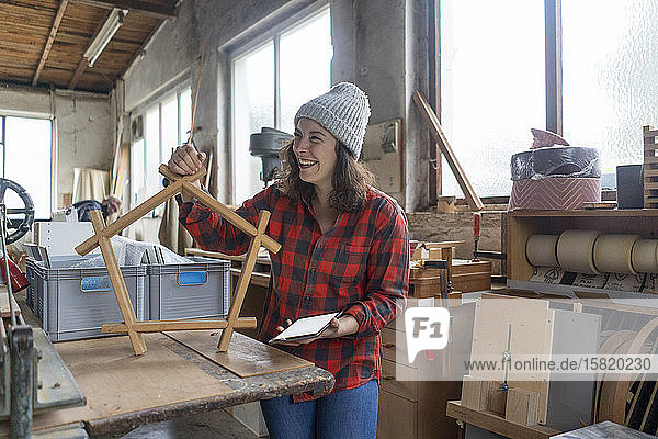 Happy carpenter holding workpiece in her workshop