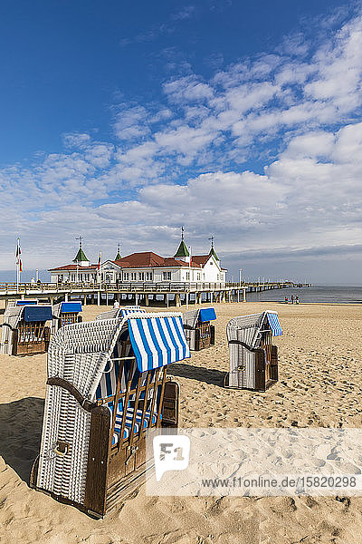 Deutschland  Mecklenburg-Vorpommern  Heringsdorf  Kapuzenstrandkörbe am sandigen Küstenstrand mit Pier im Hintergrund