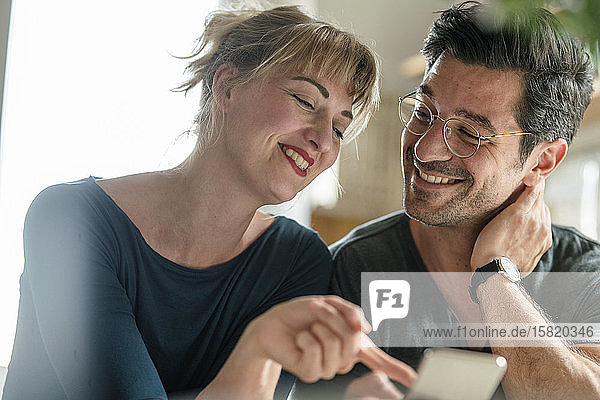 Happy couple using smartphone at home