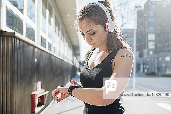Sportliche junge Frau mit Smartwatch in der Stadt