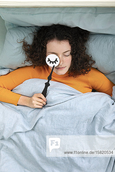 Porträt einer schlafenden jungen Frau im Bett liegend mit Papiermaske