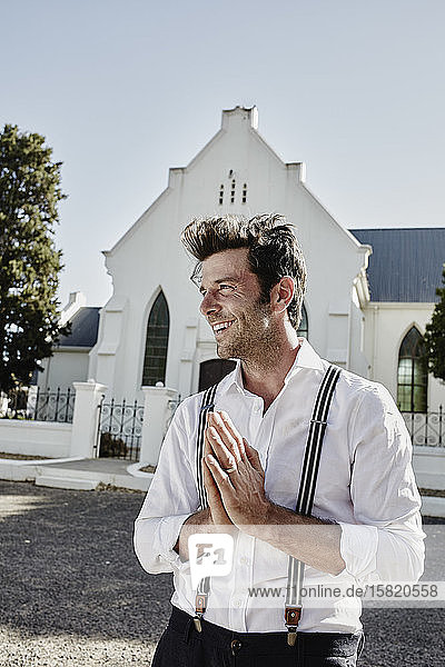 Glücklicher Mann in altmodischer Kleidung auf dem Land beim Gebet in einer Kirche
