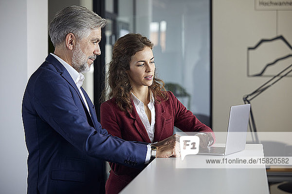 Businessman and businesswoman working together on laptop in office
