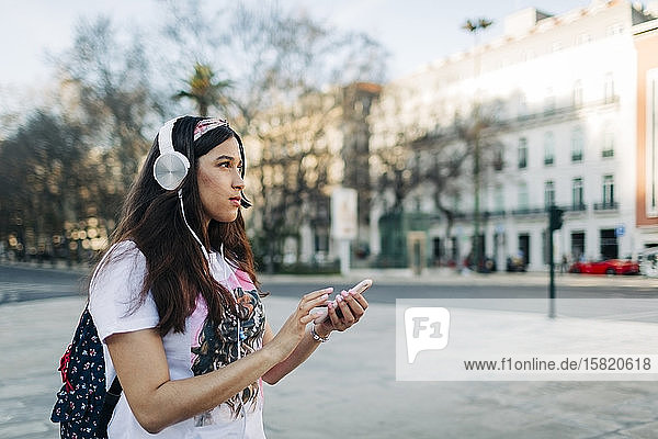Junge Frau mit Kopfhörern am Mobiltelefon