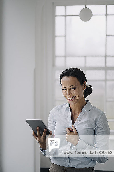 Erfolgreiche Geschäftsfrau  am Fenster stehend  mit digitalem Tablet  lächelnd