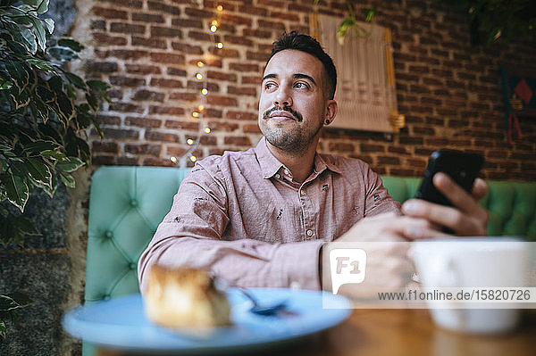 Portrait of a man in a cafe holding cell phone