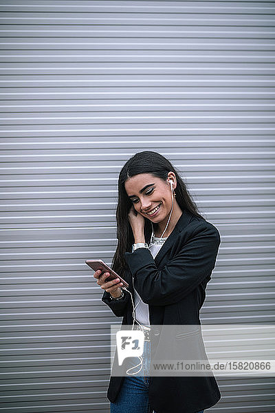 Porträt einer glücklichen jungen Frau mit einem Smartphone und Kopfhörern