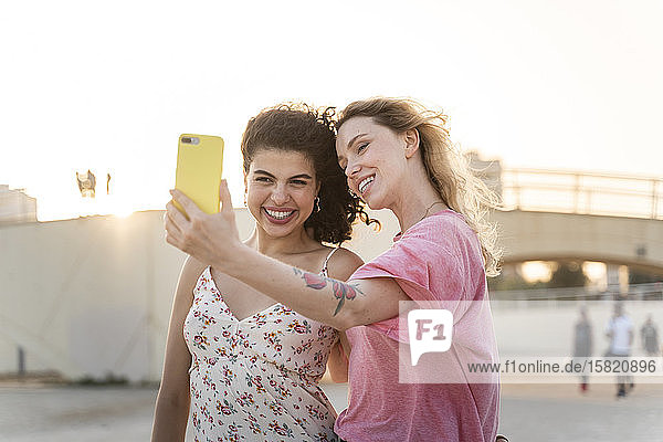Happy friends taking a selfie outdoors at sunset